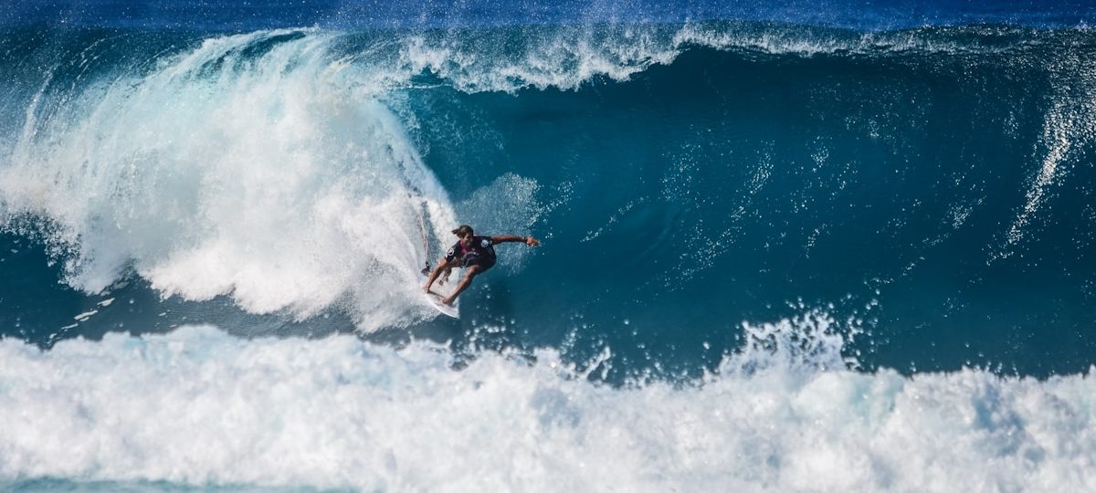 Surfeur en combinaison épaisse sur une grande vague de houle hivernale