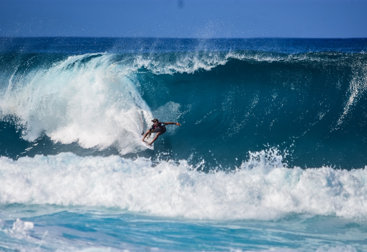 Surfeur en combinaison épaisse sur une grande vague de houle hivernale